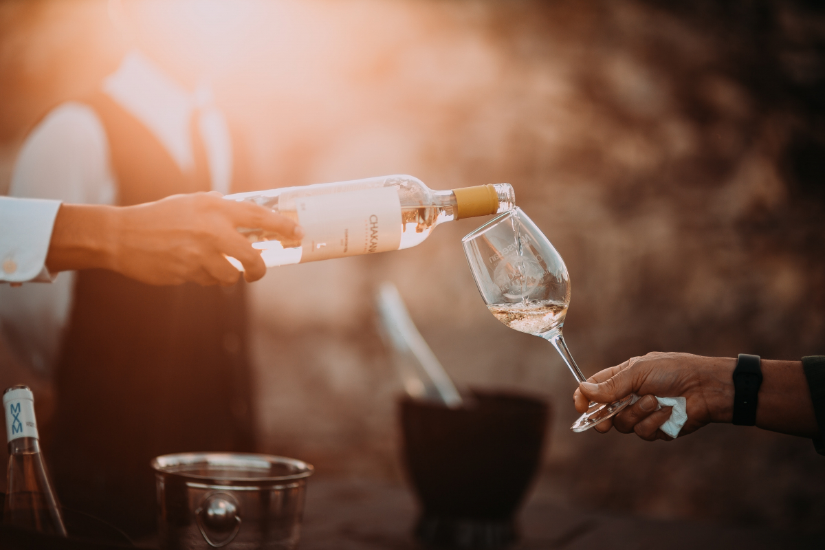 Photo of a bottle of wine being poured into a glass. The photo is by Douglas Lopez on Unsplash